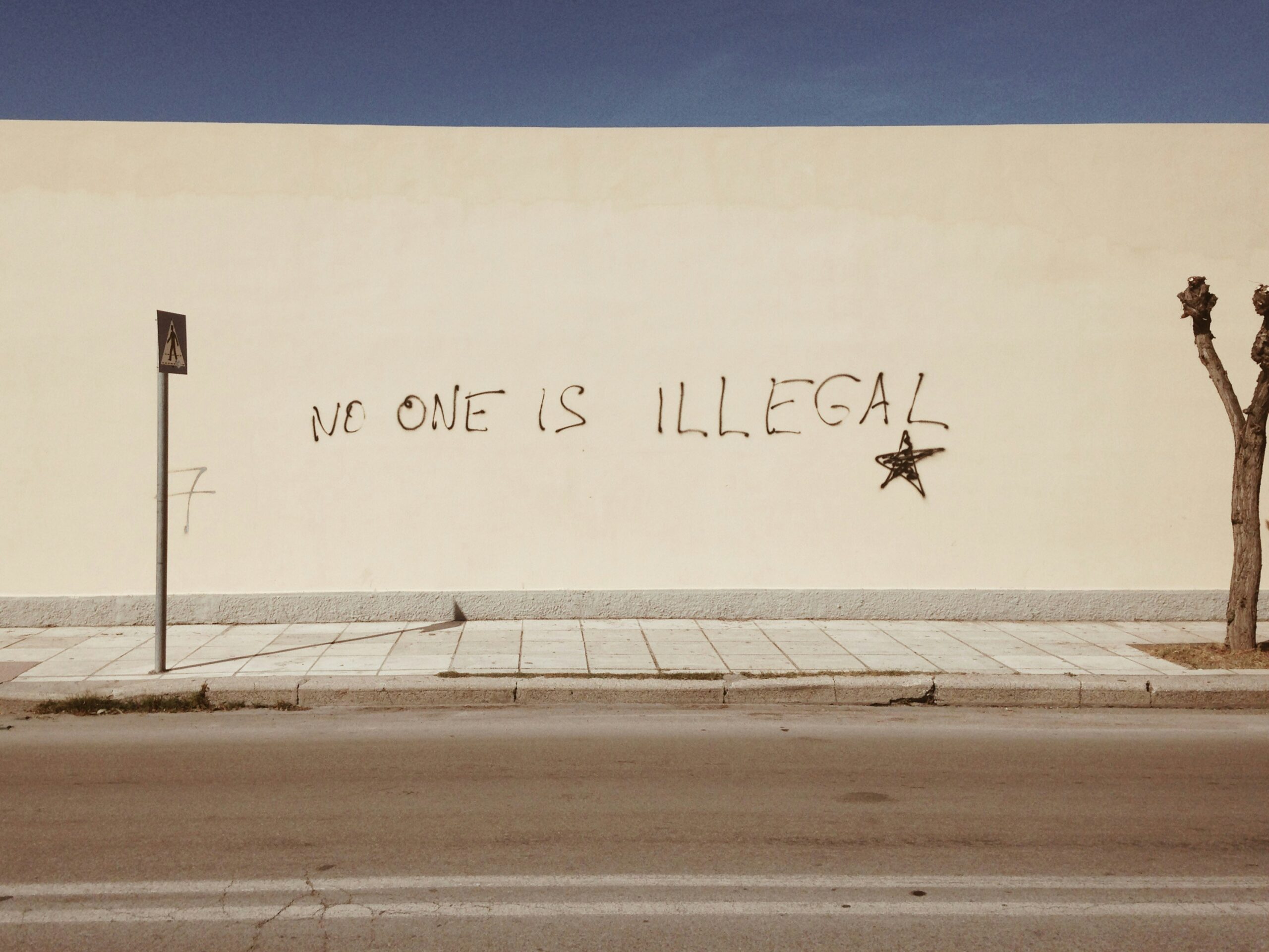 Foto von einer Mauer mit einem Graffito mit dem Text "no one is illegal